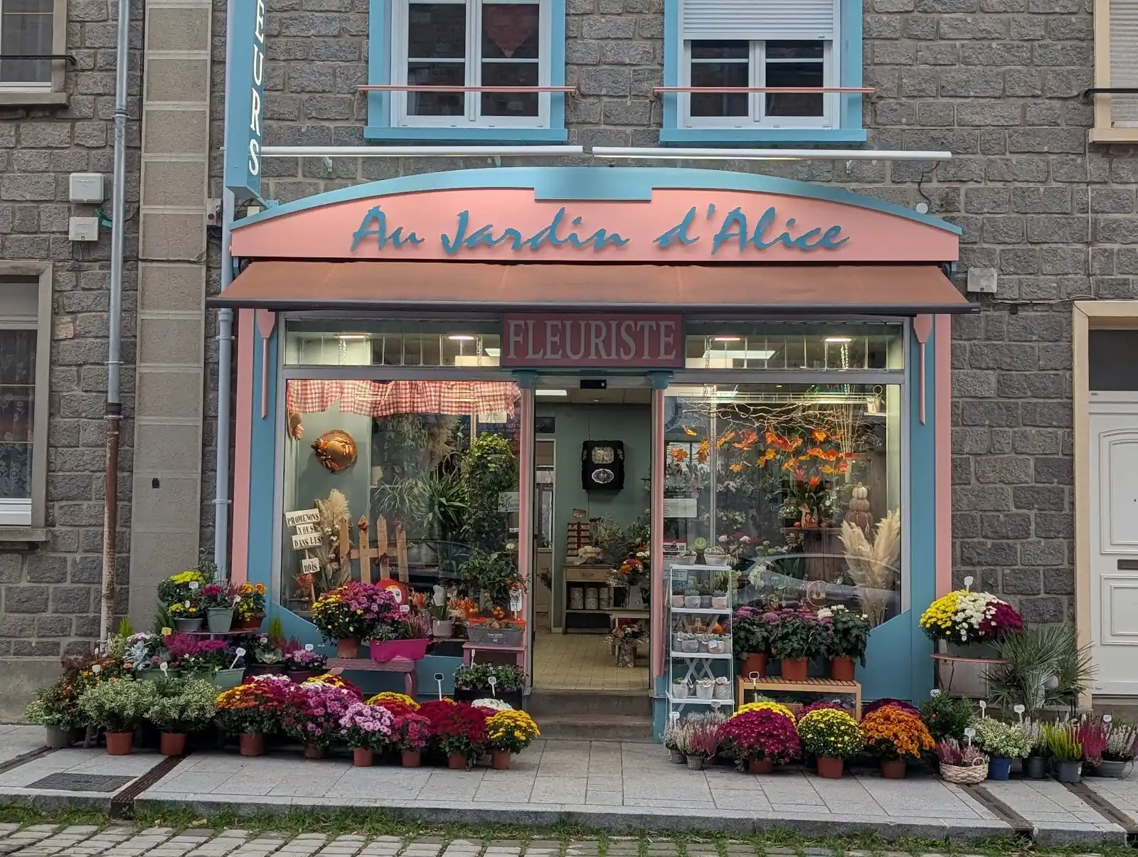 Devanture rose de la boutique et fleurs exposées sur le trottoir