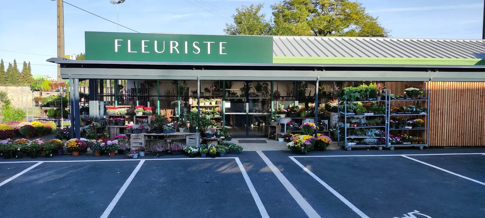 Façade de la boutique avec son enseigne Fleuriste et son parking