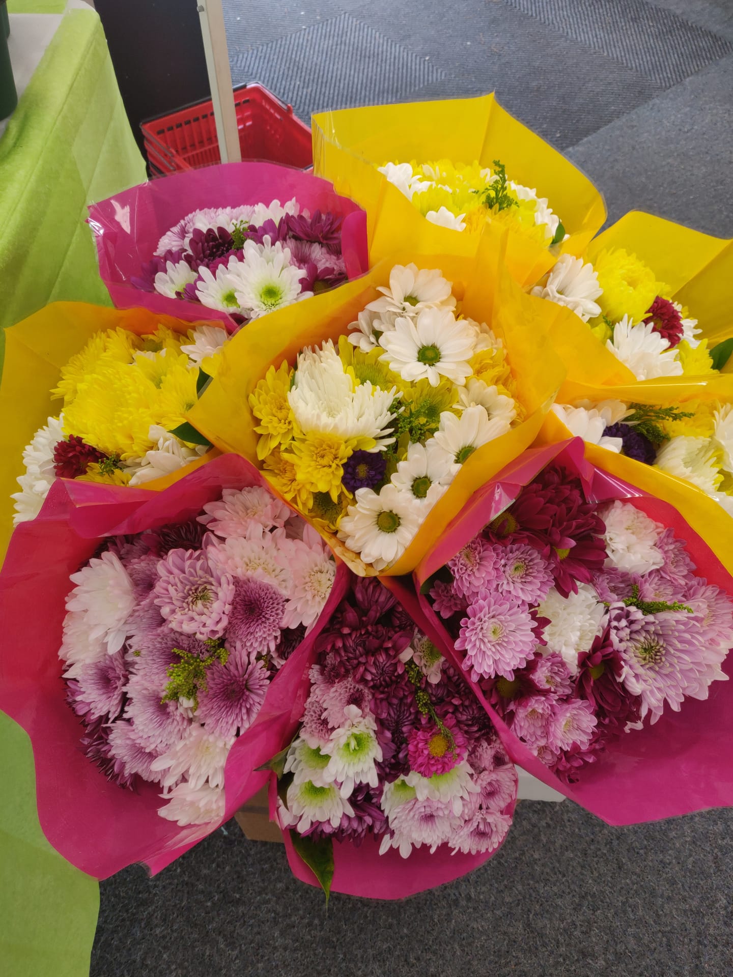 Des bouquets de marguerites et de chrysanthèmes emballés dans du papier jaune et rose