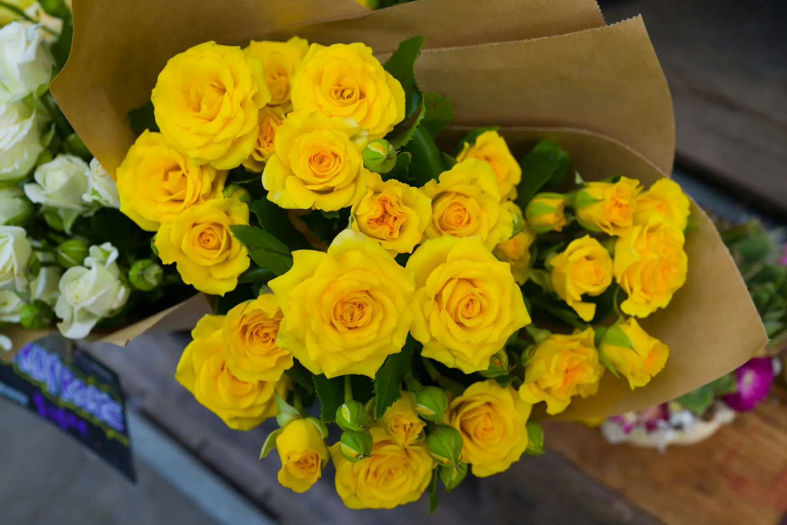 Bouquet de roses jaunes posé sur une table en bois, en gros plan avec feuillage vert
