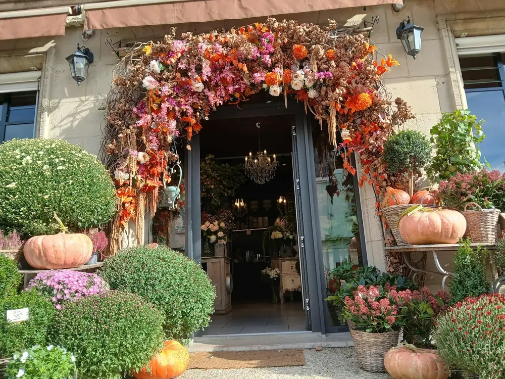 Entrée de la boutique décorée d’une arche de fleurs d’automne et de citrouilles