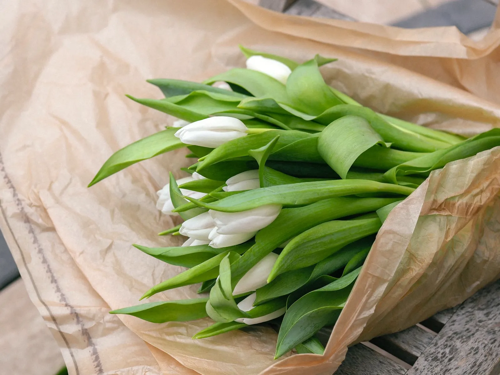 Bouquet de tulipes blanches enveloppé dans du papier kraft