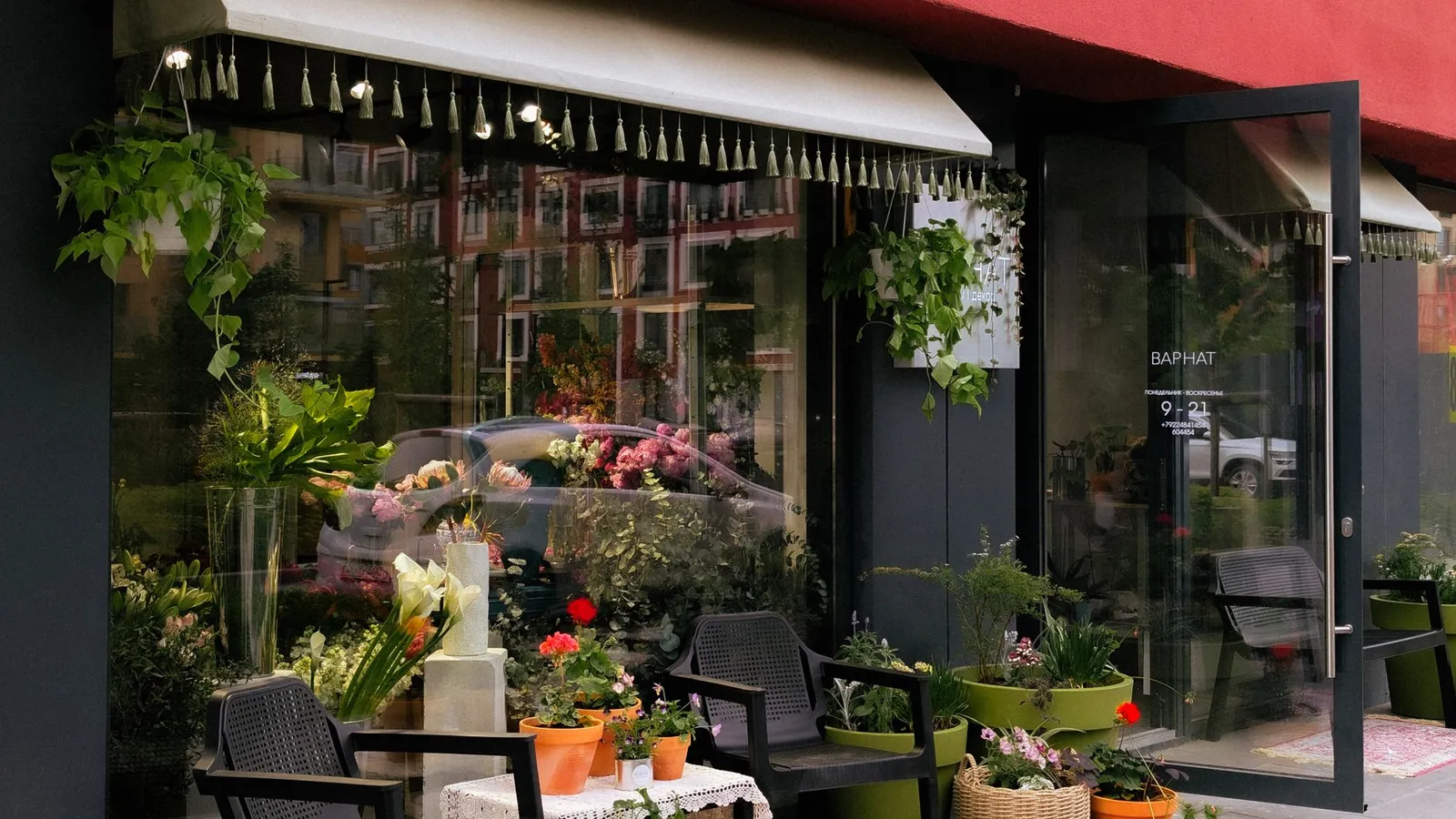 Façade d’une boutique de fleurs avec plantes et bouquets disposés sur le trottoir, devanture éclairée