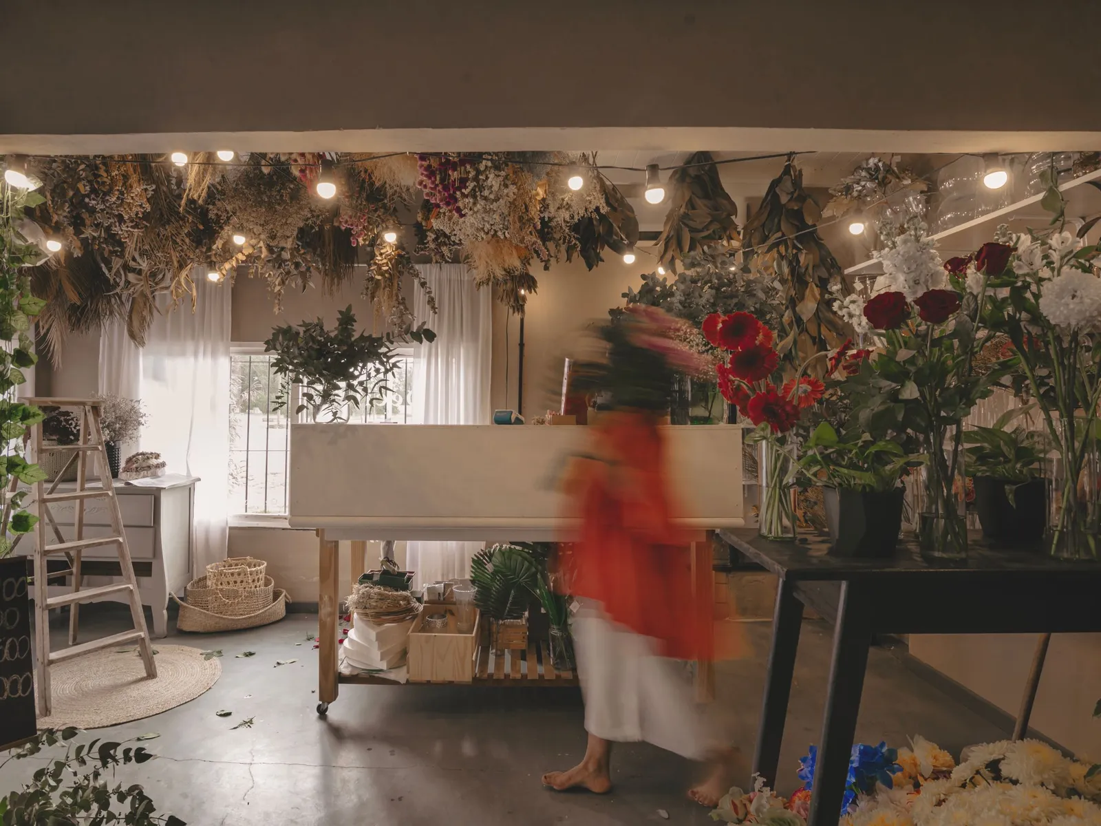 Intérieur lumineux d'une boutique de fleurs avec des bouquets séchés suspendus au plafond et des guirlandes lumineuses