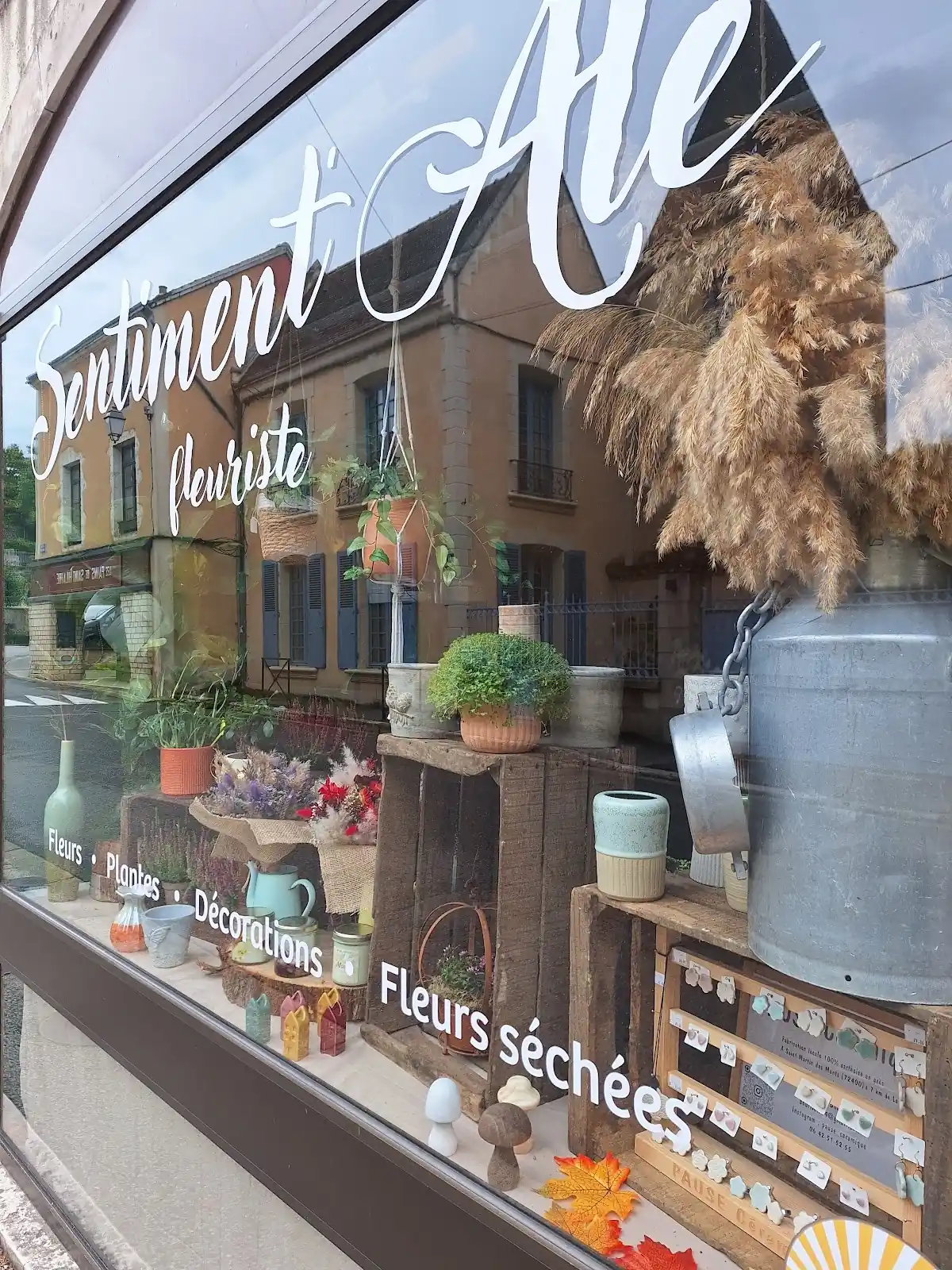 Vitrine de la boutique avec son nom peint et des fleurs séchées