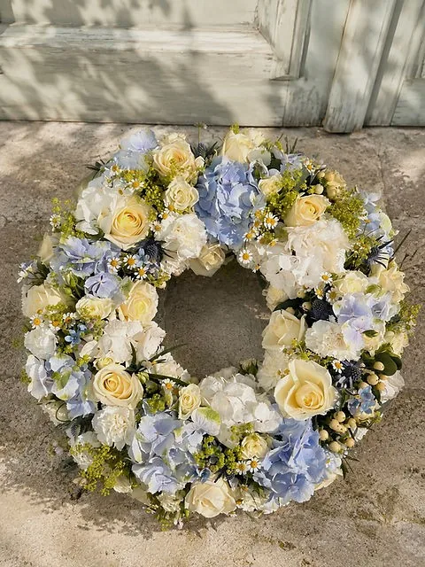 Couronne de deuil en fleurs blanches, jaunes et bleues